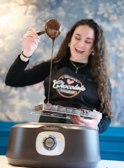 Chocolatier pouring melted Belgian chocolate into a mold during a Ghent chocolate workshop