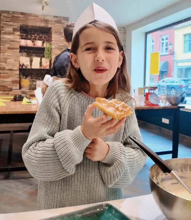 Happy young girl enjoying a freshly baked Belgian waffle at our Ghent workshop